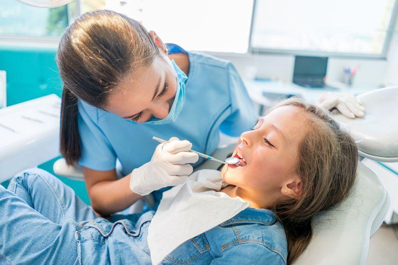 Dentystka robiąca przegląd jamy ustnej dziecka